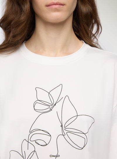 T-shirt con stampa volto e farfalle